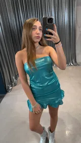 Vestido corto strapless color turquesa brillante, con efecto plisado y volados en el dobladillo.