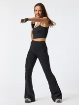 Calza flare deportiva de tiro alto color negro, confeccionada en poliéster con spandex. Presenta pretina ancha, bolsillos laterales y una pequeña apertura en el dobladillo inferior de cada pierna.