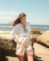 Shorts de brocato con estampado floral en tonos rosados y beige, con terminación de flecos en el ruedo.