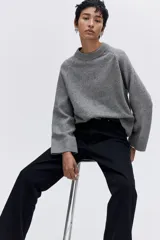 Sweater de punto suave con corte holgado, mangas raglán y cuello redondo. Presenta terminaciones acanaladas en cuello, puños y bajo.