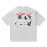 Remera blanca de algodón con corte oversize y estampado en la espalda de una playa con palmeras y una silla de playa.