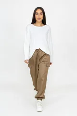 Babucha estilo cargo color beige, con corte holgado, cintura elástica con cordón ajustable, bolsillos laterales funcionales y puños elásticos en los tobillos.