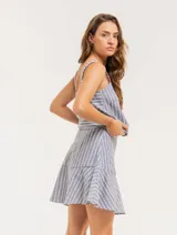 Falda corta color beige con rayas verticales blancas, corte evasé y volado en el ruedo.