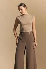 Top sin mangas de tejido texturizado con brillo integrado, color beige dorado, con cuello alto y hombros levemente estructurados.