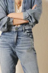 Jean de corte mom fit, tiro medio-alto y calce holgado, con pierna recta que ajusta hacia el ruedo. Confeccionado en denim azul con un lavado claro, localizado, con bigotes. En los bolsillos traseros lleva un bordado de alas.