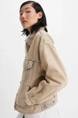 Campera de jean estilo trucker, color beige, con cierre frontal de botones metálicos, bolsillos con solapa en el pecho y costuras reforzadas.