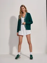 Cárdigan de punto verde oscuro con cuello en V y botones. Presenta ribetes blancos en el cuello, el frente y los puños.