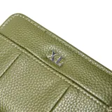 Billetera de tamaño compacto en color verde oliva, confeccionada en material símil cuero con textura granulada. Presenta un diseño con costuras verticales decorativas y el logo metálico de la marca en la parte frontal. Cuenta con cierre perimetral.