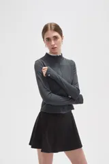 Campera deportiva de ajuste entallado, confeccionada en poliéster color gris oscuro. Presenta cuello alto, cierre frontal completo y mangas largas con aberturas para los pulgares.