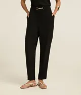 Pantalón negro de corte zanahoria, con cintura elástica, adorno metalizado en la cintura y bolsillos laterales.