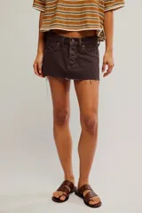 Minifalda de denim rígido marrón, de tiro bajo y calce relajado, con diseño de cinco bolsillos, cierre de botones y ruedo desmechado.