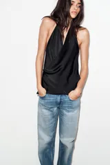 Top de satén con cuello halter, diseño drapeado en el frente y bajo asimétrico. Presenta espalda descubierta y cierre con lazada en el cuello.