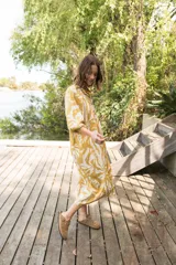 Vestido midi de corte camisero con estampado floral en tonos verde agua y crema. Presenta cuello a la base, cierre frontal con botones y mangas al codo con terminación elástica.