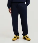 Pantalón jogger negro de algodón y poliéster, con cintura elástica y cordón ajustable. Presenta bolsillos laterales y puños ajustados en los tobillos.