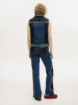 Pantalón de denim color tostado con tiro alto y corte oxford. Presenta detalles de apliques metalizados a lo largo de las costuras laterales y en los bolsillos.