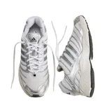 Championes Adidas Adistar Control 3 de diseño técnico, con base de malla blanca y superposiciones en color plata metalizado. Presenta entresuela amortiguada en tono crema y suela de goma negra con diseño de tracción.