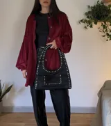 Sobrecamisa de plush color bordó, con corte holgado, mangas largas abullonadas con puños elásticos y cierre frontal con botones a tono.