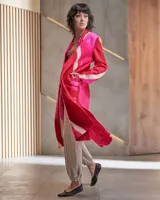 Tapado largo de lana merino afieltrada, color fucsia con diseño tie-dye artesanal en tonos claros y crudos. Tiene cuello que se prolonga a modo de cinto, aberturas laterales y bolsillos.