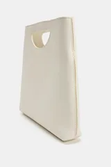 Bolso de mano de piel color rojo, con diseño de cuerpo asimétrico y asa de mano integrada con apertura lateral. Incluye correa bandolera extraíble y bolsillo interior.