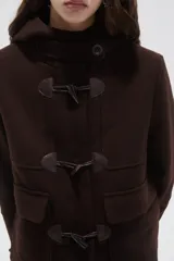Campera tipo duffle coat de lana en color verde oliva, con capucha, cierre frontal mediante botones tipo toggle y bolsillos delanteros con solapa.