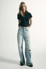 Camisa de denim entallada con cuello solapa, escote en pico y manga corta. Presenta costuras marcadas y cierre frontal con botones.
