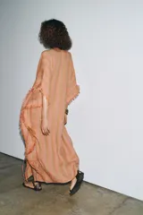 Vestido largo tipo kaftán confeccionado en lino a rayas verticales en tonos naranja y verde. Tiene cuello redondo con escote en V, mangas cortas amplias, acabado deshilachado y cinturón de cordón en el mismo tejido.
