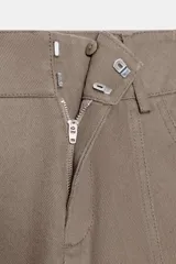 Pantalón cargo de tiro alto color marrón topo, con pierna ancha y holgada que se estrecha hacia el tobillo. Presenta bolsillos delanteros, bolsillo de plastrón lateral y falso bolsillo de vivo en la espalda.