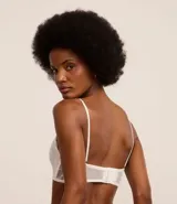 Soutien femenino modelo top de encaje floral blanco, sin copa, sin aro y con tirantes ajustables.