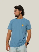 Remera de algodón blanca con cuello redondo y manga corta, presenta un pequeño estampado de un fruto de mburucuyá en el lado izquierdo del pecho.