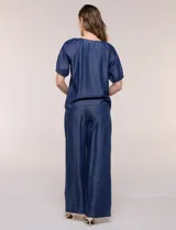 Blusa de calce relajado de lyocell en tono azul denim, con cuello a la base y cierre frontal de botones metálicos. Tiene mangas cortas abullonadas con puños elásticos.