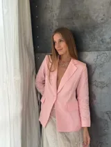 Blazer sastrero de lino en color rosa pastel, con cierre frontal de un botón forrado, solapas clásicas y bolsillos laterales con solapa. Presenta un corte estructurado y forro interior de algodón.