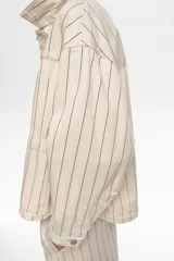 Chaqueta corta de corte línea A confeccionada en mezcla de algodón, con diseño a rayas, cuello camisero, mangas largas, bolsillos delanteros tipo plastrón y cierre frontal.