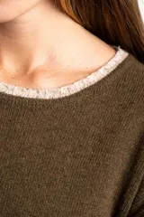 Sweater de lana con diseño de rayas horizontales blancas sobre fondo verde oliva. Presenta cuello redondo, mangas largas con puños acanalados y un corte oversize con tajos laterales en el ruedo.