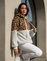 Buzo tipo canguro de polar, con diseño combinado en animal print de leopardo en la parte superior y color gris claro en la parte inferior. Cuenta con capucha, cordones ajustables y cierre frontal.