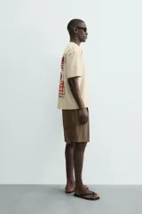 Camiseta relaxed fit color beige, con cuello redondo y manga corta. Presenta un bordado y estampado combinado a contraste en el delantero y la espalda.