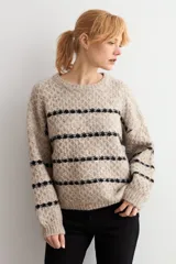 Sweater de punto con textura, color beige melange con rayas horizontales negras. Presenta cuello redondo, mangas largas y corte holgado.