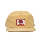 Gorra tipo snapback de corderoy color amarillo, con visera plana y corona baja sin estructura. Presenta un parche frontal bordado con el logo de la marca y un zorro.