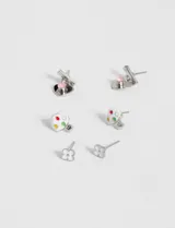 Set de tres pares de caravanas plateadas con diferentes dijes: corazón con piedra rosa, paleta de pintor con manchas de colores y trébol de cuatro hojas.