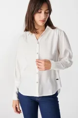 Camisa de corte relajado color blanco, con cuello clásico, cierre frontal de botones y mangas largas con puños ajustados y volumen en los hombros.