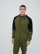 Campera deportiva Umbro de diseño bicolor en verde militar y negro, con capucha con cordón ajustable, cierre frontal completo y bolsillos tipo canguro. Presenta mangas ranglán de color negro con una franja verde y detalles estampados en los brazos.