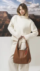 Cartera tipo hobo de cuero sintético color tostado, con diseño de hombro, costuras verticales decorativas y monedero pequeño extraíble a tono.