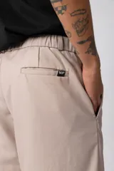 Pantalón sastrero de corte baggy, color beige, con pinzas frontales, cierre de botón y cremallera, y bolsillos laterales.
