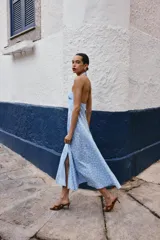Vestido midi de algodón con estampado de lunares blancos sobre fondo celeste. Presenta cuello halter con cierre de botones y espalda descubierta, con un corte evasé fluido.