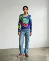 Remera de manga larga con cuello redondo, confeccionada con una estampa exclusiva de formas orgánicas y abstractas en tonos azul, verde, turquesa y magenta.
