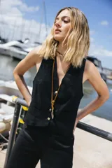 Chaleco de lino negro con escote en V, cierre frontal con botones y bolsillos delanteros simulados.