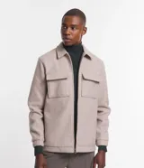 Campera pesada tipo trucker de polivelour color beige, con cuello camisero, cierre frontal por cremallera y dos bolsillos frontales con solapa en el pecho.
