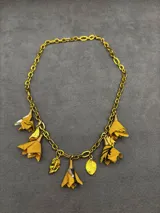 Collar de cadena dorada con dijes colgantes en forma de flores textiles amarillas con detalles estampados y hojas metálicas doradas.
