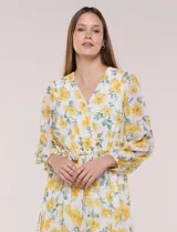 Vestido maxi de gasa con estampado floral en tonos amarillos y verdes sobre base blanca, escote en V cruzado, mangas largas y cintura elastizada con lazo.