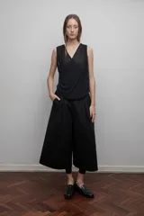 Bermuda sastrera negra unisex de popelina o gabardina de algodón, con pretina elástica, tiro bajo, bolsillos laterales, cierre lateral y pliegue delantero de gran tamaño.