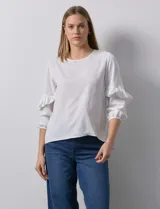 Blusa de gasa estampada con flores azules y violetas sobre fondo blanco, de manga 3/4 con volados.